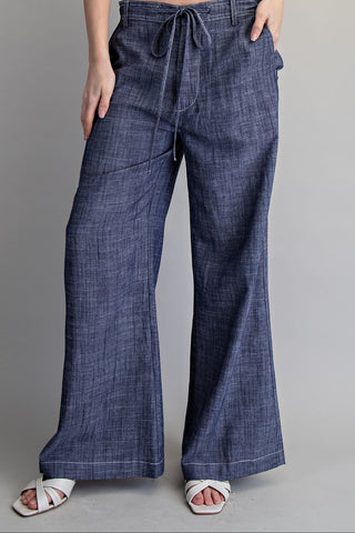 Blue denim wide-leg pants worn by a person on a gray background
