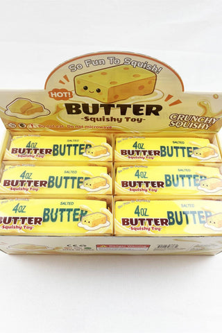 A retail display box filled with individually wrapped Butter Squishy Toy candies. The packaging features a cartoon cheese character and the text 'Butter Squishy Toy' and 'Crunchy Crunch'.