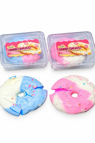 Two donut-shaped squishies with frosting swirls and sprinkles, shown with their clear plastic storage containers on a white background. One donut is blue and white with multicolor sprinkles, and the other is pink and white with multicolor sprinkles.