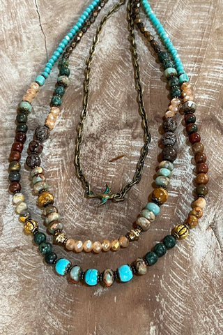 Three beaded necklaces on a textured wooden surface