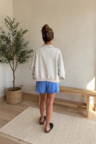 woman wearing gray sweatshirt blue shorts back view