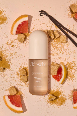 Kitsch hair product bottle with vanilla beans and grapefruit slices on a beige background