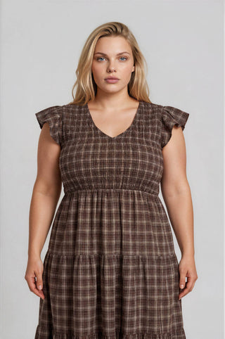 Woman wearing a brown plaid dress against a plain background