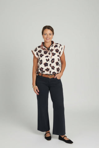 A woman modeling a short-sleeve leopard-print blouse and black wide-leg trousers.