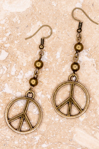 Peace symbol earrings with beads on a beige background