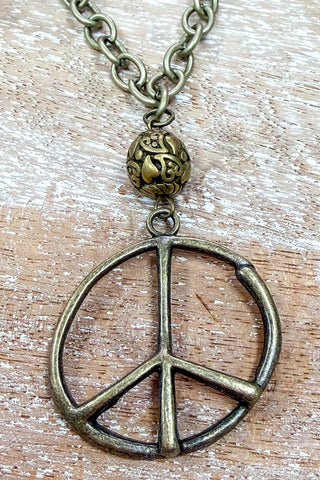 Bronze peace symbol necklace on a wooden surface