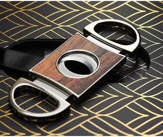 Cigar cutter with wooden finish and metal handles on a patterned surface