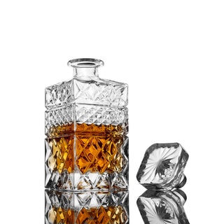 Crystal decanter with diamond pattern filled with amber liquid on a white background