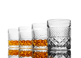 Set of four crystal glasses with diamond cut design on a white background