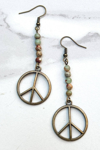 Peace sign earrings with beaded strings on a marble background