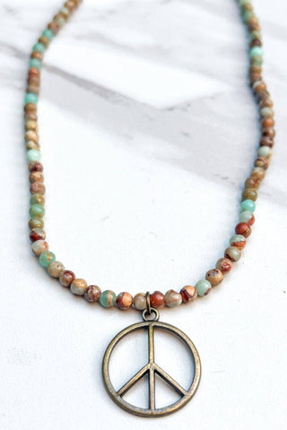Necklace with bead chain and peace symbol pendant on a white background