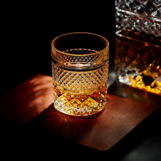Decorative glass filled with a amber liquid on a dark surface