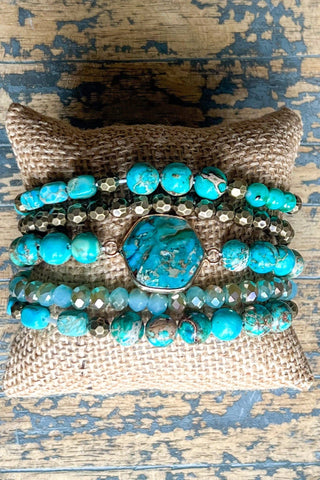 Stack of turquoise beaded bracelets on a textured fabric surface