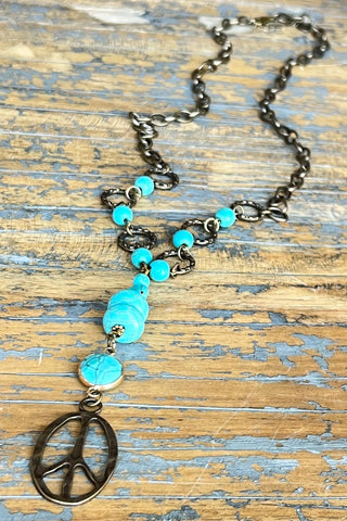 Necklace with turquoise beads and peace symbol pendant on a wooden surface
