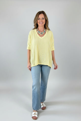 Woman wearing a yellow top and blue jeans.