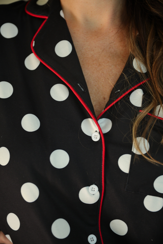 Close-up of a black polka dot pajamas with red piping.