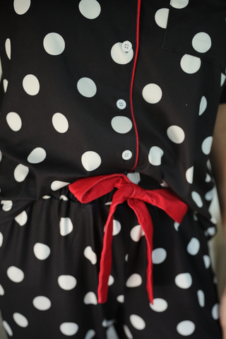 Black pajamas with white polka dots and a red tie waist.