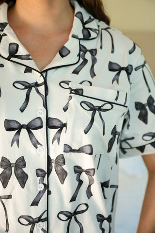 White pajama top with black bow pattern worn by a person.