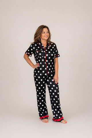 Woman wearing a black polka dot pajama set on a plain background