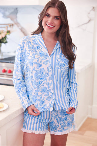 Woman wearing a blue floral pajama set in a kitchen.