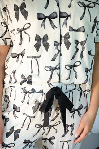 White pajamas with black bow pattern with black tie bow on pants