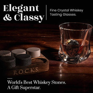 Fine crystal whiskey tasting glasses with whiskey stones on a wooden coaster.