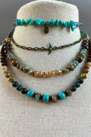 Set of beaded necklaces on a mannequin bust against a neutral background