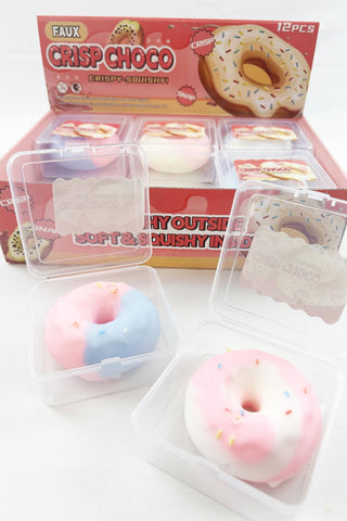 A boxed set of faux donut squishies with three clear plastic clamshell cases containing pink-and-blue, pink-and-white, and white-and-pink donut toys, shown in front of a red retail box labeled 'FAUX CRISP CHOCO'.
