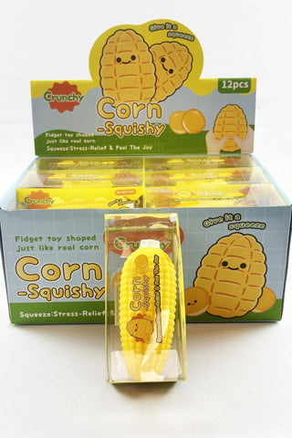 A box of Crunchy Corn-Squishy fidget toys, showing a clear plastic package with one yellow corn-shaped toy in front of an open display box with multiple matching toys inside.