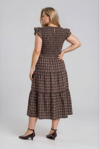 Woman wearing a brown checkered dress on a white background