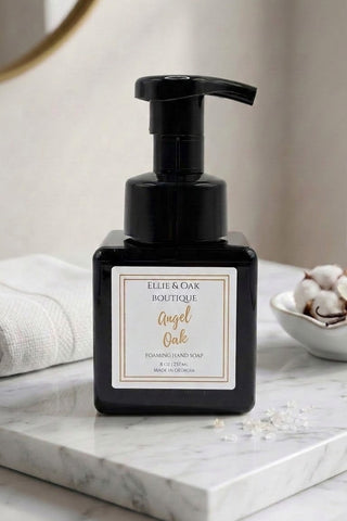 Ellie & Oak Boutique Angel Oak Dehydrating Hand Soap in a matte black pump bottle, styled on a white marble tray with a folded white towel and cotton bolls in the background.