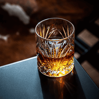 Glass of whiskey on a dark surface with a blurred background