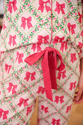 Patterned outfit with pink bows and green leaves on a neutral background