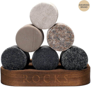 Stack of round stone coasters on a wooden stand with 'ROCKS' engraving.
