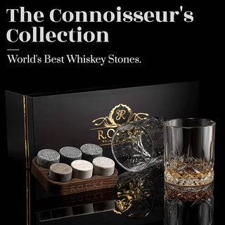Whiskey stones set with a glass and branded box on a reflective surface.