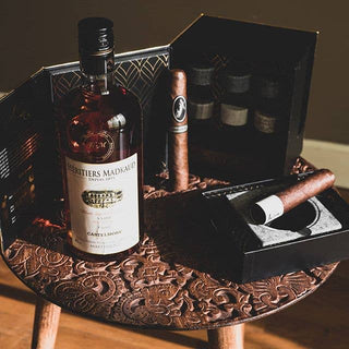 Bottle of Berthier's Madmaud cognac with two cigars on a decorative wooden tray.
